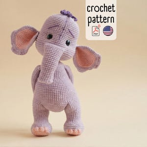 Puede incluir: Un elefante de ganchillo hecho a mano en tonos morados y rosas. El elefante tiene orejas grandes, una trompa y ojos negros pequeños. La imagen incluye el texto "crochet pattern" y un icono PDF con una bandera estadounidense.