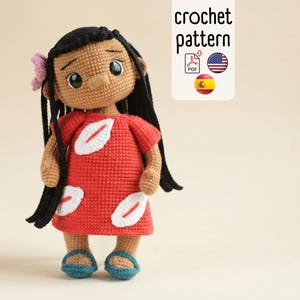 May include: A crocheted doll with black hair, a red dress with white leaf-shaped accents, and blue sandals. The doll has a tan complexion and a pink flower in its hair. The image includes a sign that says "crochet pattern".