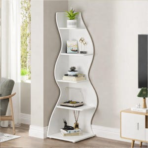 May include: White corner bookshelf with a distinctive wave design. The shelves display decorative items such as a small potted plant, books, and a record player. The bookshelf is positioned in a corner of a room with a window and a chair.