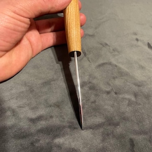 Puede incluir: Un picahielos con mango de madera clara y hoja de acero pulido. El mango es cil&iacute;ndrico, con una virola de metal oscuro. La hoja es fina y termina en punta. Longitud total aproximada de 15 cm.