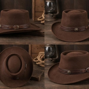 May include: A dark brown felt hat with a flat crown and a wide brim. The hat features a decorative brown leather band around the base, accented with braided detailing, a small metal buckle, and a circular metal stud on the side.