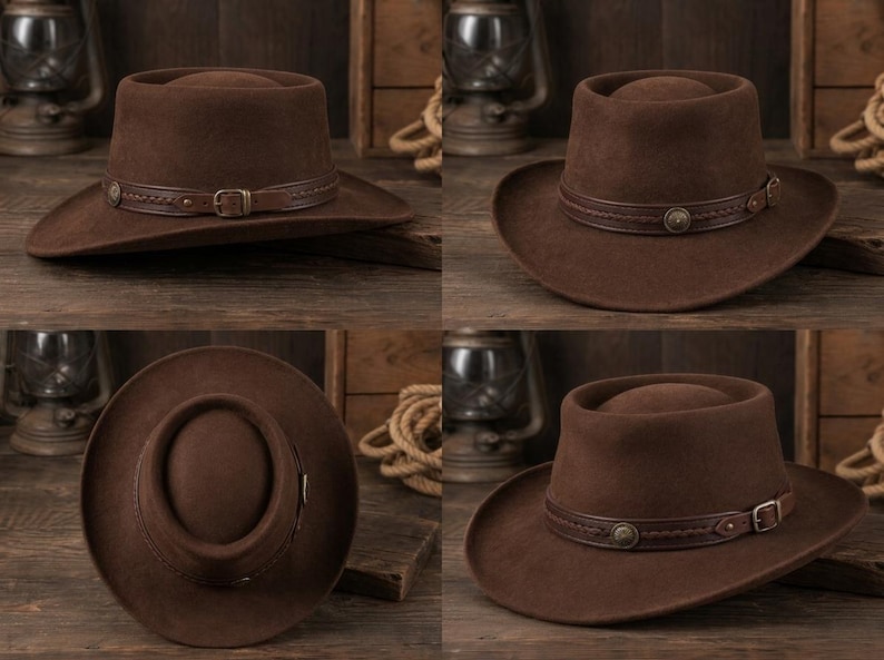 May include: A dark brown felt hat with a flat crown and a wide brim. The hat features a decorative brown leather band around the base, accented with braided detailing, a small metal buckle, and a circular metal stud on the side.