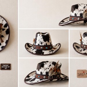 May include: A western hat with a black and white cow print pattern, featuring a brown leather band with turquoise accents, metal studs, and decorative feathers. The hat is accompanied by a tag that reads COWPRINT WESTERN TOP HAT.