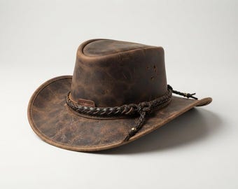 May include: A dark brown distressed leather cowboy hat featuring a braided leather hatband with a small metal accent. The hat has a pinched crown, a wide brim, and visible ventilation eyelets on the side of the crown, showcasing a textured finish.