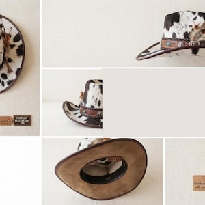 May include: A western hat featuring a black and white cow print pattern, a brown leather band with silver-toned accents, and decorative feathers. The interior is lined with a tan material. A tag displays the text: COWPRINT WESTERN TOP HAT.