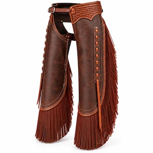 May include: Dark brown leather chaps featuring a woven pattern on the upper belt section, a buckle closure at the waist, and long, thin fringe detailing along the outer edges of each leg. The design includes vertical leather lacing accents.
