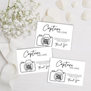 May include: Three white rectangular cards with black text and line art. Each card features the phrase Capture the Love, a camera illustration with a QR code, and the text Please scan the QR code to share your wedding photos with us. Thank You.