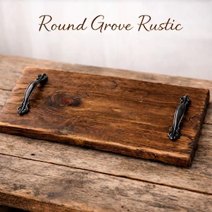 May include: A rectangular wooden serving tray with dark brown stain and black metal handles. The tray has the text "Round Grove Rustic" in a brown script font. The tray is on a rustic wooden surface.
