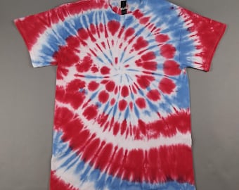 May include: A short-sleeved t-shirt with a spiral tie-dye pattern in red, white, and blue. The design radiates from the center, with alternating bands of color. The shirt has a crew neck and a standard fit.