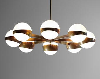 May include: A modern chandelier with eight spherical frosted glass shades, each encircled by a brass band. The fixture has a central hub and radiating arms, all in a brass finish, suspended from a single rod.