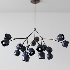 May include: Modern chandelier with a bronze finish and navy blue shades. The light fixture has multiple arms extending from a central point, each holding a downward-facing light. The shades are cylindrical and have a glossy finish.