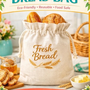 May include: A beige bread bag with a drawstring closure, filled with two golden-brown loaves of bread. The bag has the words "Fresh Bread" and wheat stalks printed on it. The top banner reads "Handcrafted BREAD BAG".