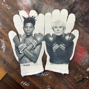 May include: Pair of white cotton gloves with black and white images of two boxers. One glove features a portrait of a man with dreadlocks, the other a man with light hair. Both are wearing boxing gloves.