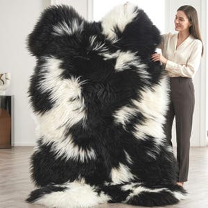 May include: A large, rectangular rug with a shaggy texture. The rug features a striking pattern of black and white, with the colors irregularly distributed across the surface. The rug is held up by a person.