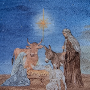 May include: A printed napkin featuring a nativity scene with a figure in a blue robe kneeling beside a manger, a figure in a brown robe standing nearby, a brown cow, a donkey, and two white lambs under a bright yellow star in a blue sky.