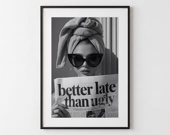 May include: A black and white framed wall art print featuring a person wearing a towel wrapped around their head and dark cat-eye sunglasses. The person is holding a newspaper with the bold text "better late than ugly" printed on the front page.