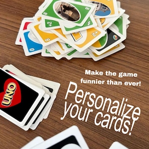 May include: A selection of Uno playing cards, displaying different colours and numbers. The cards are arranged on a wooden surface, with some stacked and others spread out. Text on the cards reads "UNO" and "+4". The image also includes the text "Personalize your cards!"