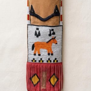 May include: A beaded Native American pouch with a tan suede top and a red bottom with fringe. The pouch features a horse design in the center, with geometric patterns and beadwork in various colors.