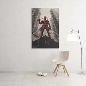 May include: A framed canvas print depicting a red superhero with swords, set against a cityscape. The artwork is mounted on a white wall, above a chair and a floor lamp. The print is a striking piece of wall art.