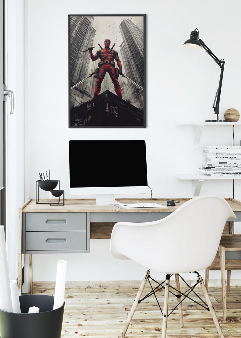 May include: A framed print depicting a red costumed figure with two swords, posed on a rooftop, with a cityscape backdrop. The print hangs above a desk with a computer and a white chair. The buildings are in shades of grey.