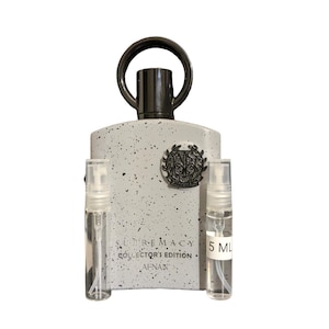 May include: A perfume bottle with a speckled gray finish, a dark handle, and the text "SUPREMACY COLLECTOR'S EDITION AFNAN." Two small spray bottles are in front of the perfume bottle.