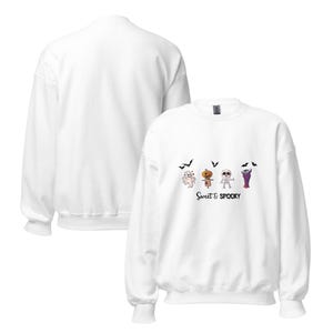 Könnte beinhalten: Ein weißes Langarm-Sweatshirt mit Rundhalsausschnitt und einem Grafikdruck, der einen Geist, eine Figur mit Kürbiskopf, ein Skelett und einen Vampir zeigt, ergänzt durch kleine schwarze Fledermäuse und den Schriftzug "SWEET & SPOOKY".