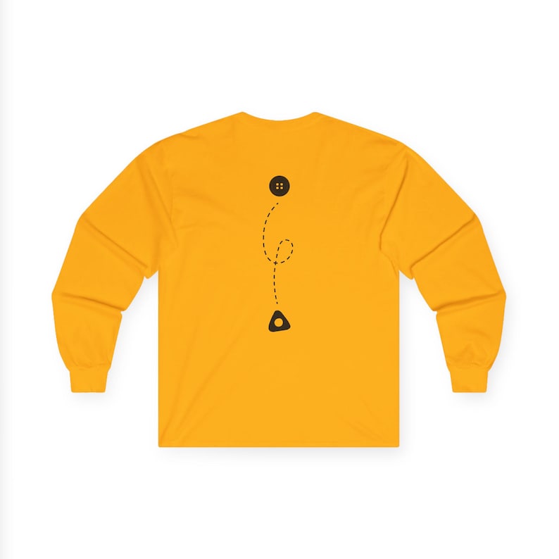May include: Mustard yellow long-sleeve shirt with a black button and a dotted line design. The design includes a black triangle shape at the bottom. The shirt has a crew neck and long sleeves.