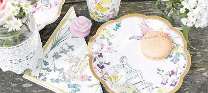 May include: A set of white paper plates with a gold rim and a floral design featuring fairies and butterflies. The plates are perfect for a whimsical party or tea party.