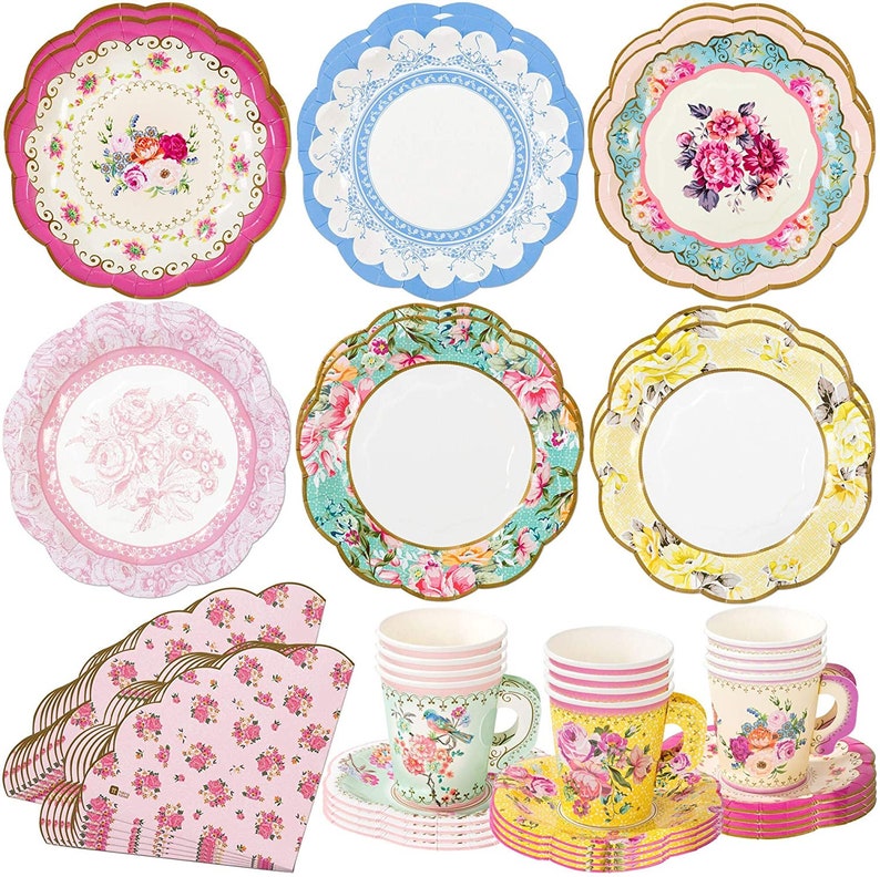 May include: A set of vintage-inspired paper party supplies, including plates, napkins, and cups. The plates feature floral designs in pink, blue, and yellow. The napkins are pink with a floral pattern. The cups are white with floral designs and come with matching saucers.