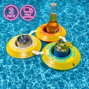 Puede incluir: Tres flotadores amarillos y rosas para bebidas en una piscina. Cada flotador tiene un diseño circular con las palabras "DRIFT N SIP" en verde. Uno sostiene una botella de cerveza, otro un vaso con pajita y el tercero un vaso azul con una guarnición de lima y menta.