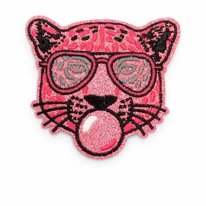 May include: A pink glittery patch in the shape of a leopard's head wearing sunglasses and blowing a bubble. The patch has black embroidered details for the eyes, nose, mouth, and sunglasses frames. The bubble is also pink and glittery.