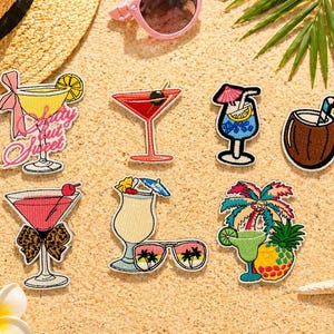 May include: A collection of embroidered cocktail patches in various designs, including a martini, a coconut drink, and a margarita. The patches feature bright colors and tropical themes, perfect for adding flair to clothing or accessories.