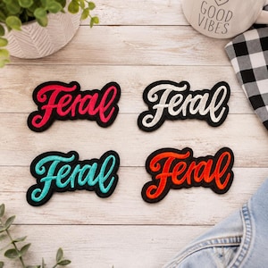May include: Four embroidered patches featuring the word Feral in cursive script. The patches have black borders and come in four distinct thread colors: bright pink, white, turquoise, and orange. Each patch is a separate, individual item.