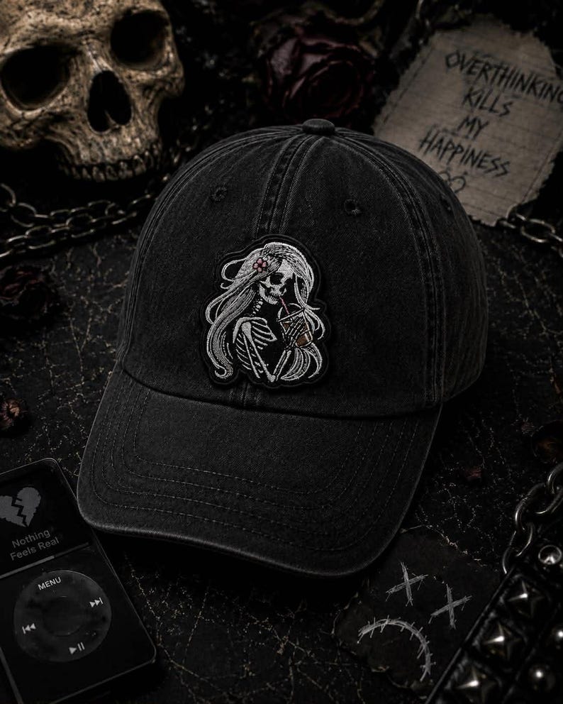 Pu&ograve; includere: Cappellino da baseball nero con una toppa raffigurante uno scheletro con lunghi capelli che tiene una bevanda. Il cappellino ha una visiera curva e un aspetto invecchiato. Il testo "Overthinking Kills My Happiness" &egrave; visibile.