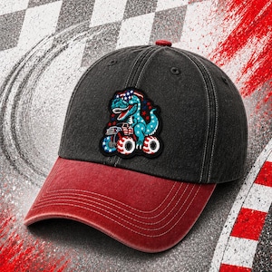 May include: A black and red baseball cap with a dinosaur graphic. The cap features a red bill and a dinosaur wearing a patriotic headband and driving a monster truck. The background has a checkered pattern and tire marks.