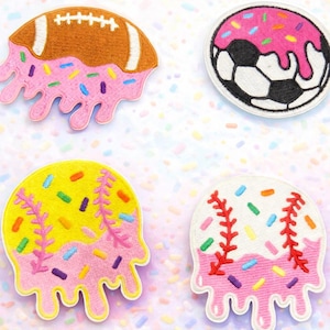 May include: Four embroidered patches with a sports theme. A football, soccer ball, and two baseballs are each topped with pink frosting and colorful sprinkles. The patches have a melted ice cream design.