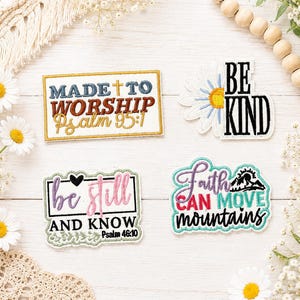 May include: Four embroidered patches with religious and inspirational text. One rectangular patch reads Made to Worship Psalm 95:1. A daisy-shaped patch reads Be Kind. A rectangular patch reads be still AND KNOW Psalm 46:10. A patch reads Faith CAN MOVE mountains.