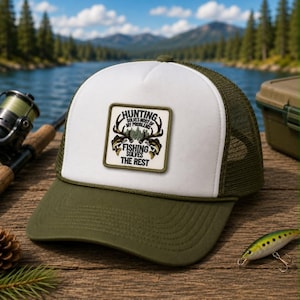 May include: An olive green and white trucker hat featuring a square patch on the front panel. The patch displays a graphic of deer antlers and fish with the text: HUNTING SOLVES MOST OF MY PROBLEMS FISHING SOLVES THE REST. The hat has a mesh back.