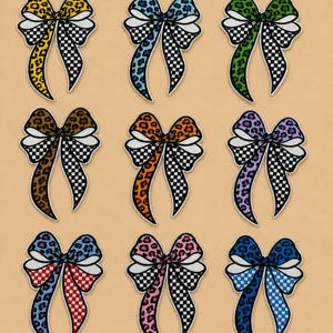 May include: Nine decorative bow appliques in various colors, including yellow, blue, green, brown, orange, purple, red, pink, and dark blue. Each bow features a leopard print center and a black and white checkered pattern on the tails.