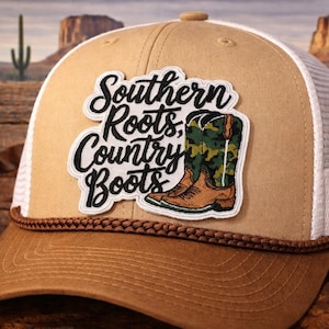 May include: Tan and white trucker hat with a brown brim and a patch that reads "Southern Roots, Country Boots." The patch features a cowboy boot with a camouflage design. The hat has a braided rope detail.