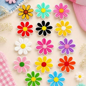 May include: A collection of fifteen embroidered flower patches in various colors including yellow, turquoise, pink, red, black, white, purple, orange, green, and blue. Each patch features a circular center and eight distinct petals.