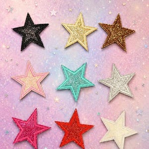 May include: A collection of nine star-shaped patches arranged in a three-by-three grid. The stars feature glittery textures in black, gold, bronze, light pink, teal, silver, hot pink, red, and cream, each with a stitched border edge.