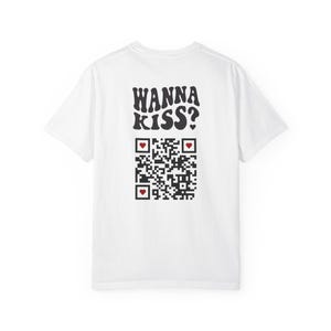 May include: White t-shirt with the text "WANNA KISS?" in black, stylized lettering. Below the text is a QR code with three red heart icons. The shirt is a casual, unisex style.