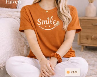 Camiseta Smile Daisy com carinha sorridente | Camiseta com estética preppy | Camiseta com estampa floral retrô | Look VSCO Girl | Presente com carinha feliz | Blusa minimalista