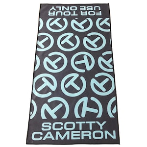 Puede incluir: Una toalla de golf rectangular negra con un patrón de logotipo azul claro repetido. La toalla tiene el texto "FOR TOUR USE ONLY" en la parte superior y "SCOTTY CAMERON" en la parte inferior.