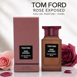 May include: A Tom Ford Rose Exposed Eau de Parfum bottle and box set. The perfume bottle is a warm brown color with a dark rose-colored cap. The box is a dusty rose color. The text "Rose Exposed" and "Eau de Parfum 100 ml" is visible.