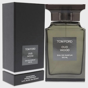 May include: A Tom Ford Oud Wood Eau de Parfum bottle and box set. The rectangular perfume bottle is clear with a dark brown cap. The box is black with white text that reads "Tom Ford Oud Wood Eau de Parfum 100 ML".