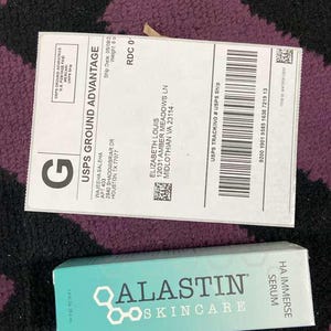 K&ouml;nnte beinhalten: Eine t&uuml;rkisfarbene Schachtel mit Alastin Skincare HA Immerse Serum neben einem USPS Ground Advantage Versandetikett. Das Versandetikett enth&auml;lt die Adresse des Empf&auml;ngers und Tracking-Informationen. Die Serumbox hat das Alastin Skincare Logo und Produktnamen.