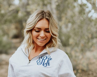 May include: A gray sweatshirt with a blue embroidered monogram "RK" on the chest. The sweatshirt has a zipper at the neck and is styled with blue jeans. The text "Amy Anne Apparel" is visible on the bottom right corner of the image.