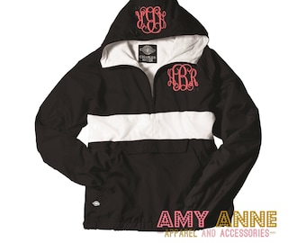 May include: Black and white hooded anorak jacket with a white stripe across the chest. The jacket has a zip closure and a drawstring hood. The jacket is embroidered with the letters "JBR" in pink on the chest and "JBR" in pink on the hood.